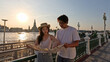© blueringmedia - Young Couple Reading Paper Map by Riverside at Sunset