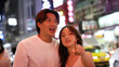 © blueringmedia - Smiling Young Asian Couple Exploring a Vibrant Urban Night Market Together