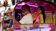 © blueringmedia - Smiling Young Couple Riding an Illuminated Tuk Tuk at Night
