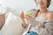 © buritora - A woman sits on a sofa and drinks lemon water, detox water.