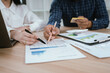 © Worawi - Business professionals reviewing financial reports and using a calculator during a budgeting meeting, analyzing costs, expenses, and business performance in a modern office.