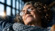© Maryna - Aged woman relaxes with eyes closed, bathed in warm natural light