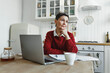 © shurkin_son - Mature intelligent female psychotherapist sitting at kitchen in front of laptop with serious facial expression looking aside table after having rest between online consultations with clients