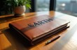 © Maryna - Brown leather journal with embossed word EARTH sits on wooden desk. Pen rests nearby, potted plant in background. Focus on eco friendly writing and planning.