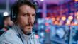 © CYBERPINK - Close-up of a man's face. he is wearing a white jacket and has a headset around his neck. he has a beard and curly hair.