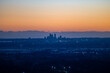 © AmazingAerialAgency - Aerial view of the Perth skyline silhouetted against a vibrant sunset sky with city lights beginning to glow across the urban landscape in Western Australia, Australia.