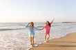 © maxbelchenko - Girlfriends enjoy the seascape at sunset. Two beautiful women are strolling along the seashore and having fun together. A concept of friendship, vacation, and freedom.