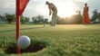 © Supardi - Close-up of a golf ball near a hole on a green, with players in background