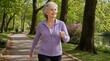 © Shakandder - A smiling senior woman with silver hair power-walks briskly along a tree-lined park path wearing a purple zip-up jacket, with spring blossoms and green foliage in the background.