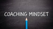 © Vivid Pixel - Coaching mindset text written with white chalk on a dark blackboard with a single blue pencil at the bottom center of the frame