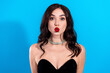 © deagreez - Glamorous young woman in black dress making a playful kiss face with red lips and choker against bright blue background