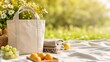 © Vasiliy - White canvas tote bag on a picnic blanket. Summer park scene with fresh fruit and flowers. Leisure and outdoor lifestyle concept