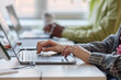 © TrueFrame Collective - Close up of young adult coworkers typing on laptops at shared desk, collaborating on digital tasks in office. Ideal for teamwork, productivity, workplace technology marketing