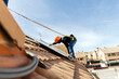 © AresStudio Belen y Carlos/Stocksy - Worker installing solar panels on residential roof
