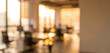 © Vhagar - A soft-focus image of a modern office setting bathed in warm sunset light. The blurred background features workspaces and large windows.