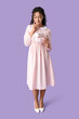 © Pixel-Shot - Beautiful young African-American woman with gift boxes on lilac background. International Womens Day