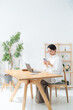 © metamorworks - 部屋でスマホとノートパソコンを使う女性。アプリ、フリーランス、仕事、ライフスタイル、DX