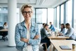 © Pixim Stock - Confident businesswoman in glasses and denim jacket smiling at camera with arms crossed in modern office, colleagues working in background, professional success and teamwork.