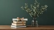 © Carlos - Graduation gift idea stacked books tied with a ribbon, next to a vase of green leaves on a wooden table against a dark green background