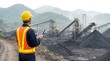 © Pixim Stock - Engineer wearing hard hat and safety vest holding tablet computer inspecting coal mine processing plant with piles of coal and conveyor belts in mountainous industrial landscape.