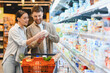 © Serhii - Couple shopping for groceries, choosing dairy products in supermarket