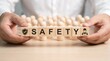 © CuteBee - Hands holding wooden blocks with word safety and icon of construction worker to promote workplace security and occupational health standards in industrial business environment