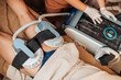 © Mdv Edwards - Aesthetic practitioner adjusts Emsculpt HIFEM body contouring device settings while applicators are positioned on a patient's buttocks for a non-invasive muscle toning treatment.