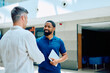 © we.bond.creations - Two diverse business professionals handshaking, smiling and collaborating in a modern office hallway, symbolizing agreement and partnership