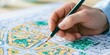 © Rifqi - Close up of professional architect hand holding pencil drawing on colorful urban planning map blueprint, representing sustainable architectural development and modern city design