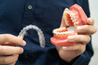 © kanruthai - Man holding invisible aligner orthodontic retainer for dental teeth straightening.