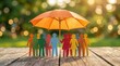 © Sukon - Concept of life and health benefit featuring diverse paper people under an orange umbrella for security.