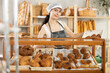 © JackF - Young female salesperson lays out fresh croissants in showcase in bakery