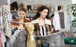 © JackF - Two girls sisters near showcase examine goods, buying something autumn outwear. Off line clothing store from retailer. Style and fashion type look, modern trends. Designer clothing store, vintage