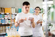 © JackF - Guy chooses pills in modern pharmacy. Female pharmacist helps with choosing a medicine