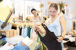 © JackF - Woman is standing in a store near a clothes rail and choosing a stylish summer dress.