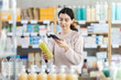 © JackF - Girl in autumn clothes scans code on medicinal shampoo to check the expiration date