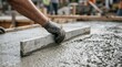 © SimpleDesignStudio - Construction worker leveling wet concrete slab with screed board for residential foundation pouring project