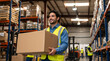© Vyatcheslav - Smiling male warehouse worker carrying a large cardboard box. Logistics employee in high-visibility safety vest at distribution center. Supply chain and shipping concept