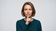 © Anwar - Portrait of a young caucasian woman making a silence gesture with finger on lips against a white background