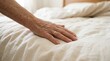 © SimpleDesignStudio - Elderly person hand resting on bed sheet representing loneliness and aging care