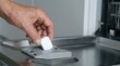 © SimpleDesignStudio - Elderly Person Placing Dishwasher Tablet into Detergent Dispenser for Household Cleaning Routine