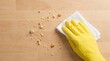 © SimpleDesignStudio - Hand in yellow rubber glove cleaning bread crumbs from wooden table surface, household chores and kitchen hygiene concept