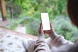 © Farknot Architect - Mockup image of a woman holding mobile phone with blank white desktop screen at home