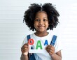© Ellfirdaus - Young girl holding colorful alphabet blocks smiling.