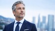 © HASANAH - Portrait of Confident Mature Businessman in Formal Suit Looking Away with Cityscape Background