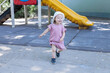 © Daria - Smiling toddler girl running in front of a playground slide. Outdoor activity supports healthy growth curiosity and active learning.