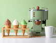 © sendok - A vibrant still life showcases a retro-style green espresso machine alongside a wooden stand displaying colorful ice cream cones, creating a playful and inviting scene.