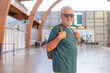 © luciano - Smiling senior adult man with a backpack and sunglasses standing in an airport terminal, embodying concepts of travel, vacation, freedom, and retirement