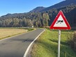 © Reinhard Pantke/imageBROKER - A country road with a warning sign for sailing leagues, under clear skies, surrounded by forests and mountains, Drau cycle path, Spittal, Carinthia, Austria