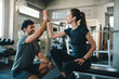 © chokniti - Couple gym fitness workout high five woman man exercise support cheerful athletes sharing high five during training session in modern health club
